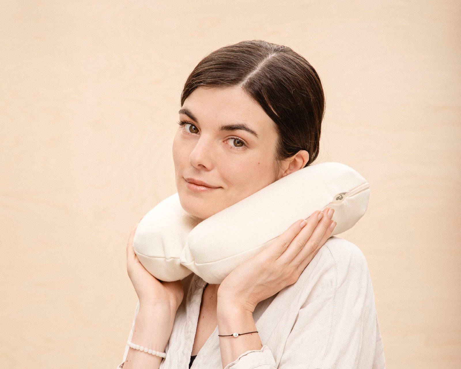 Woman resting her cheek on a small wool neck pillow