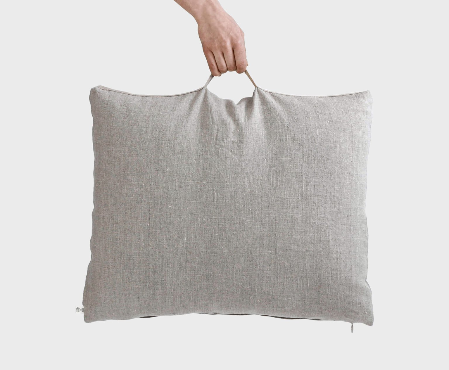 Wool travel pillow held by its carry handle