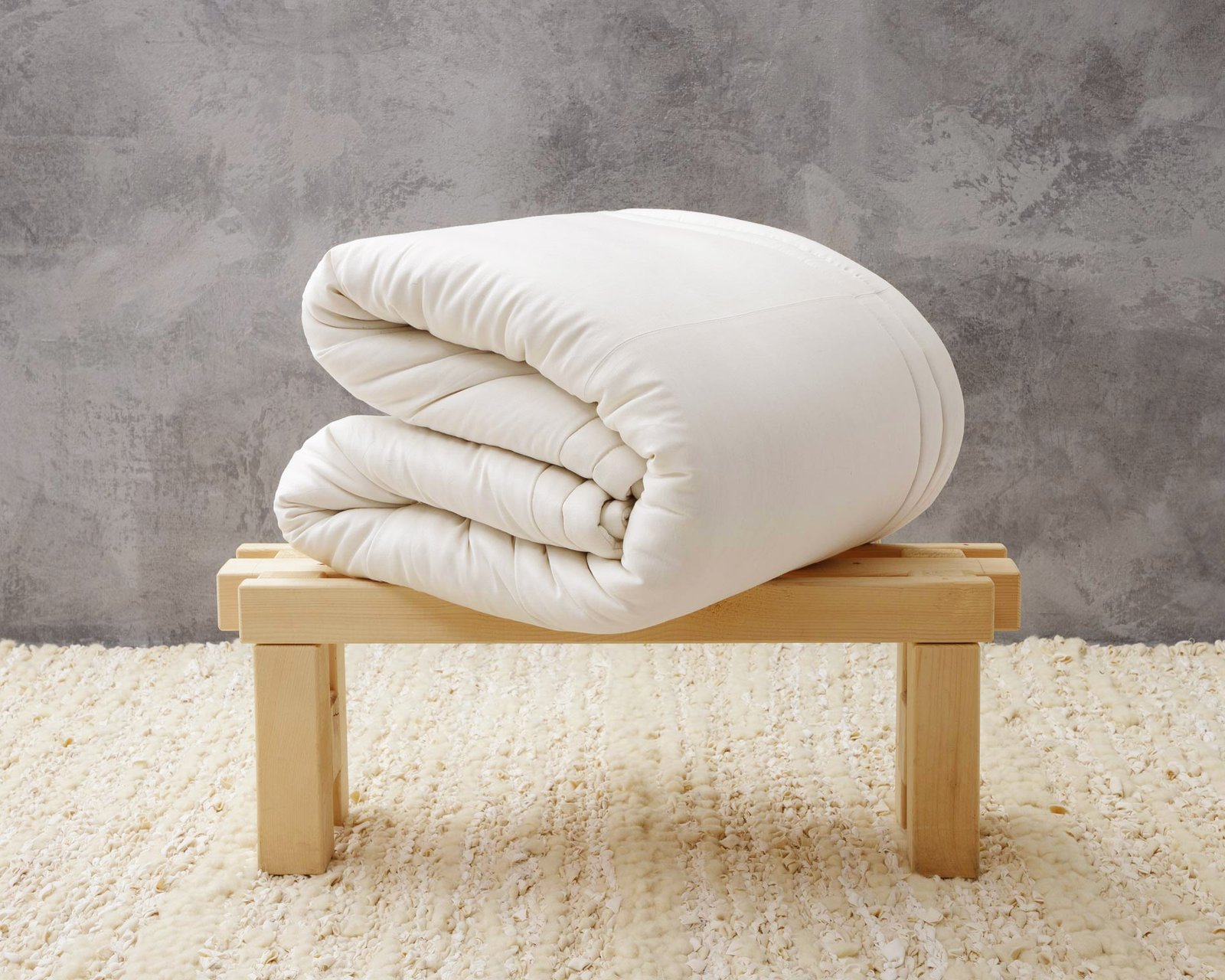 Folded wool duvet insert on a wooden bench